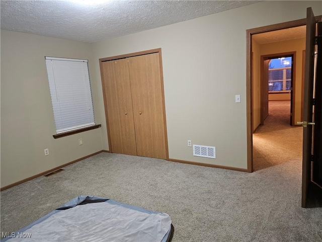 carpeted bedroom with baseboards, visible vents, a closet, and a textured ceiling