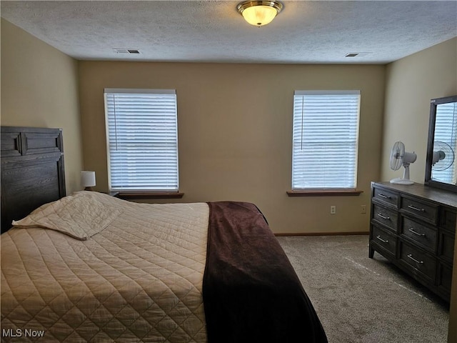 bedroom featuring baseboards, visible vents, carpet floors, and a textured ceiling