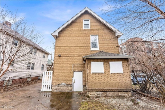 back of house featuring brick siding and fence