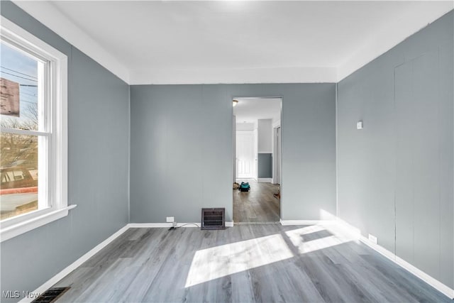 spare room featuring visible vents, baseboards, and wood finished floors