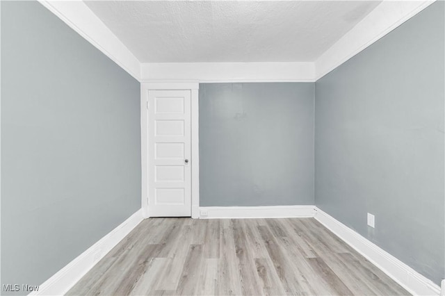 empty room with a textured ceiling, baseboards, and wood finished floors