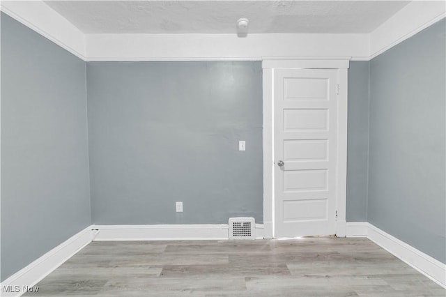 empty room featuring visible vents, baseboards, a textured ceiling, and wood finished floors