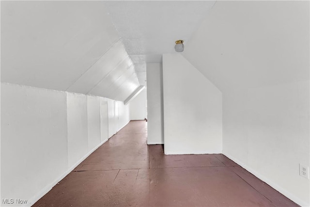 additional living space featuring concrete floors and vaulted ceiling