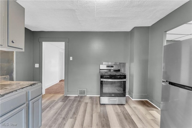 kitchen with baseboards, light wood-style floors, visible vents, and stainless steel appliances