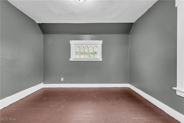 bonus room featuring a textured ceiling, baseboards, and wood finished floors