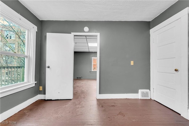 empty room featuring visible vents, wood finished floors, baseboards, and a paneled ceiling