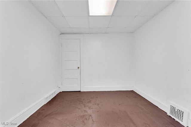 spare room with a drop ceiling, visible vents, and baseboards