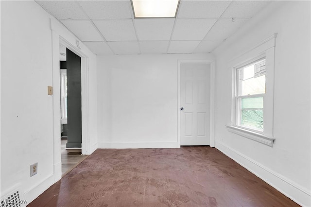 spare room featuring visible vents, a paneled ceiling, and baseboards