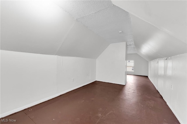 bonus room featuring baseboards, lofted ceiling, and a textured ceiling