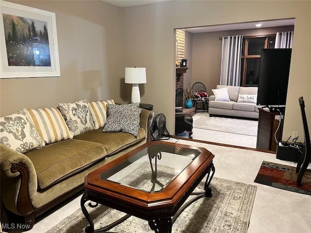 living room with a brick fireplace and carpet floors