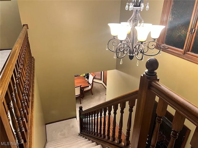 staircase with a notable chandelier, carpet, and baseboards