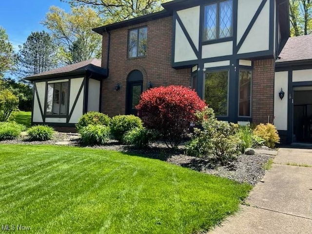 exterior space featuring brick siding, stucco siding, and a front yard