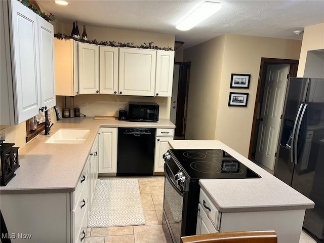 kitchen featuring black appliances, a kitchen island, light countertops, white cabinetry, and a sink