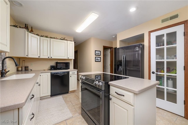 kitchen featuring visible vents, black appliances, light tile patterned flooring, white cabinetry, and a sink