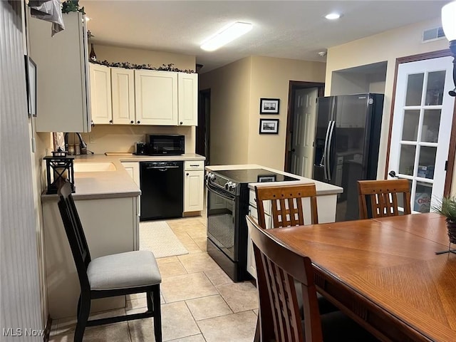 kitchen featuring visible vents, black appliances, white cabinetry, light tile patterned flooring, and light countertops