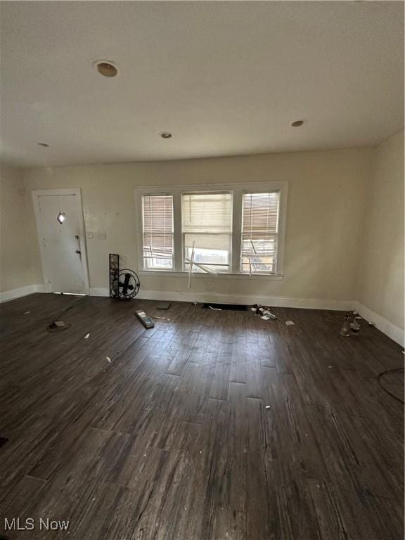 unfurnished living room featuring wood finished floors and baseboards