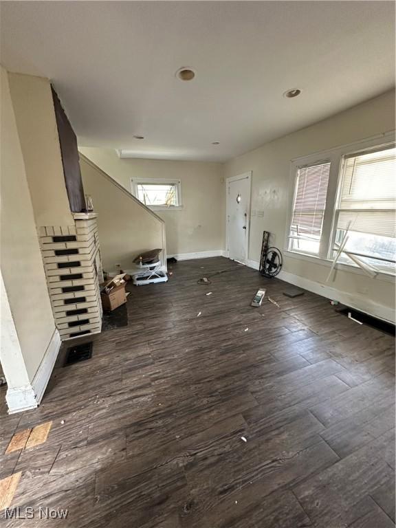 unfurnished living room featuring dark wood finished floors and baseboards