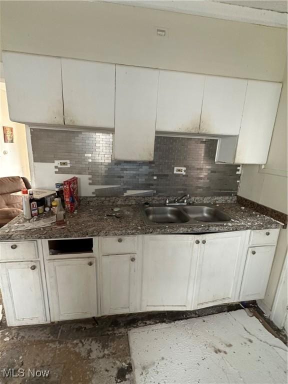 kitchen with backsplash, white cabinets, and a sink