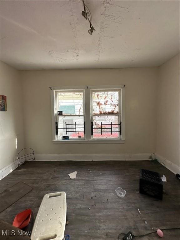 spare room with hardwood / wood-style floors, track lighting, and baseboards