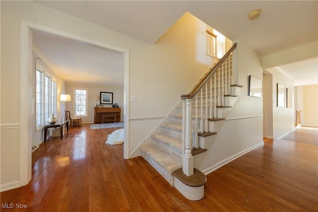 staircase with hardwood / wood-style floors, baseboards, and ornamental molding