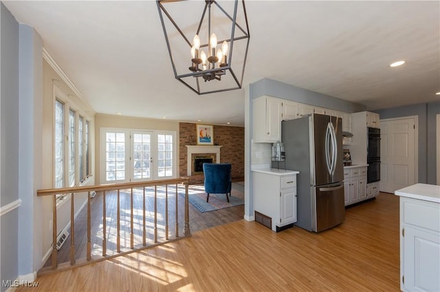 kitchen featuring light wood-style floors, light countertops, dobule oven black, and freestanding refrigerator