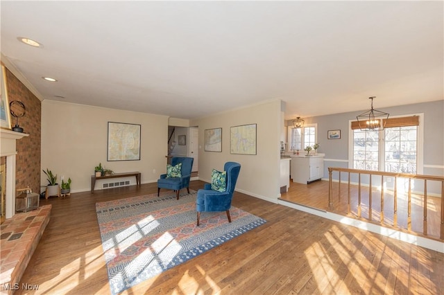 living area with a fireplace with raised hearth, baseboards, a chandelier, recessed lighting, and wood finished floors