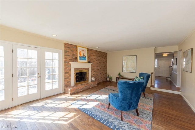 living room with baseboards, a brick fireplace, wood finished floors, and crown molding