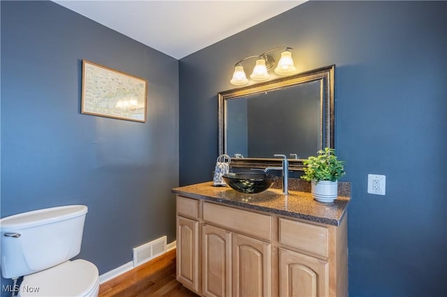 bathroom with visible vents, toilet, wood finished floors, baseboards, and vanity