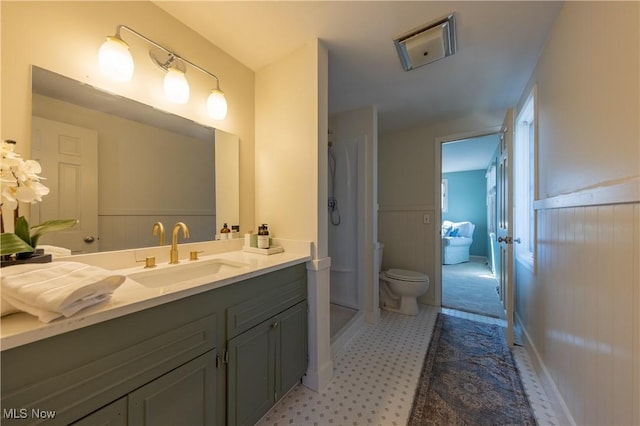 bathroom with tile patterned floors, toilet, a stall shower, wainscoting, and vanity