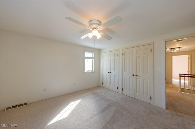 unfurnished bedroom with visible vents, carpet floors, two closets, and ceiling fan