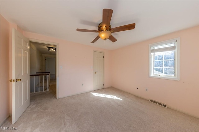 unfurnished bedroom with visible vents, light carpet, and a ceiling fan