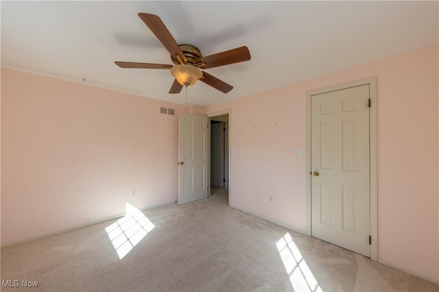 unfurnished bedroom with visible vents, light colored carpet, and a ceiling fan