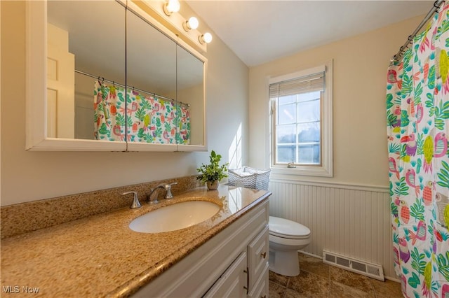 full bathroom featuring vanity, a shower with curtain, visible vents, wainscoting, and toilet