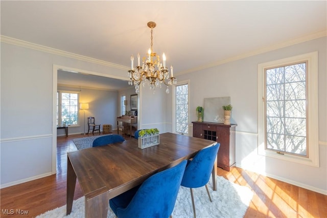 dining area with baseboards, crown molding, an inviting chandelier, and wood finished floors