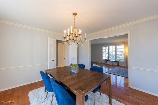 dining room featuring baseboards, a notable chandelier, wood finished floors, and ornamental molding