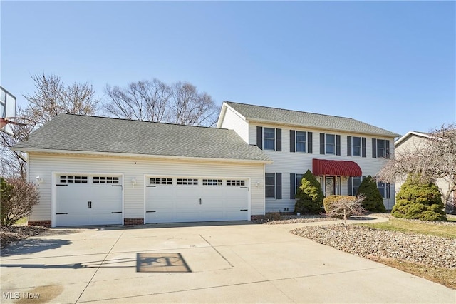 colonial house with concrete driveway, a garage, and a shingled roof