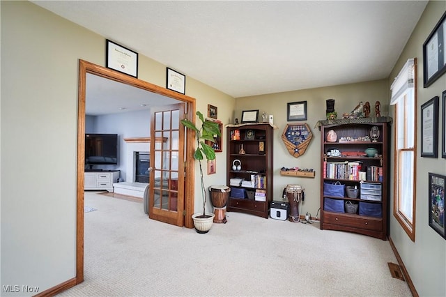 interior space featuring a glass covered fireplace, carpet flooring, and baseboards