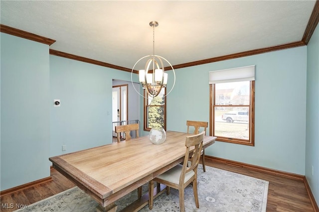 dining room with baseboards, an inviting chandelier, wood finished floors, and crown molding