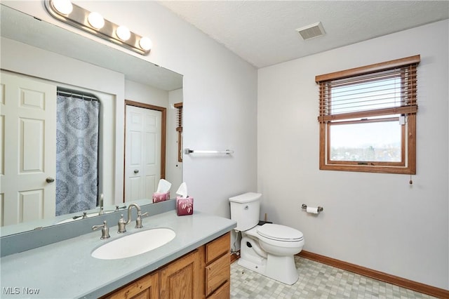 bathroom with visible vents, baseboards, toilet, vanity, and a textured ceiling