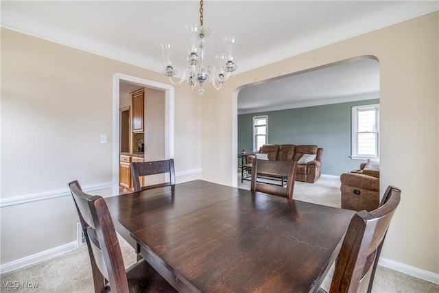 dining area with arched walkways, light carpet, and a chandelier