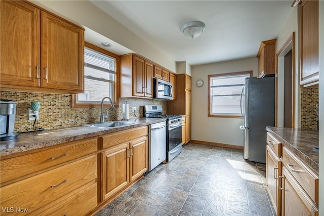 kitchen featuring a sink, brown cabinets, backsplash, and appliances with stainless steel finishes