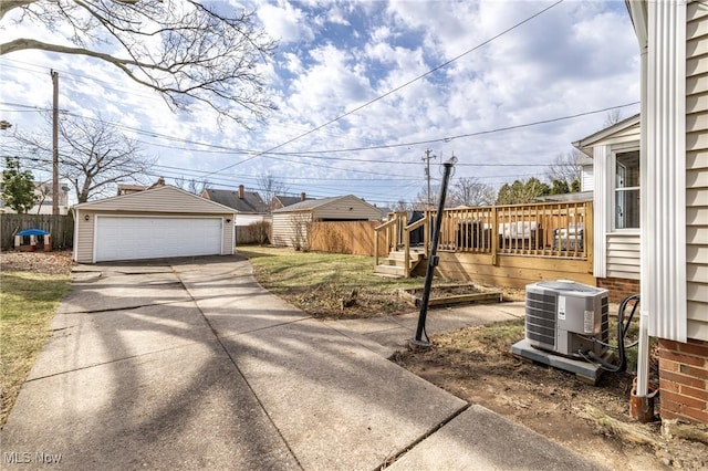 view of yard with central air condition unit, an outbuilding, a detached garage, fence, and a wooden deck