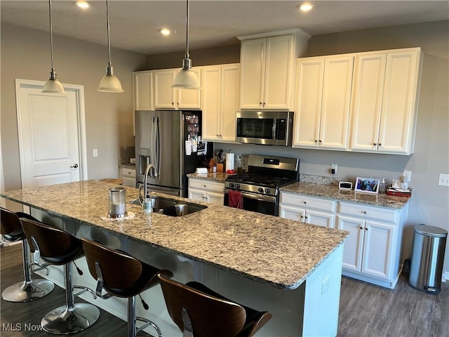 kitchen with white cabinets, wood finished floors, appliances with stainless steel finishes, and a sink