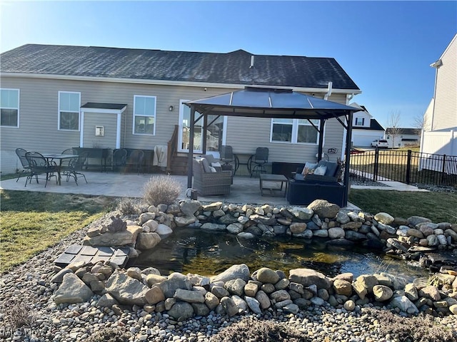 back of house featuring a gazebo, a patio area, a garden pond, and fence