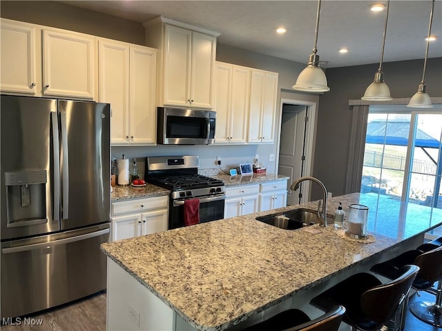 kitchen with white cabinets, a center island with sink, appliances with stainless steel finishes, and a sink