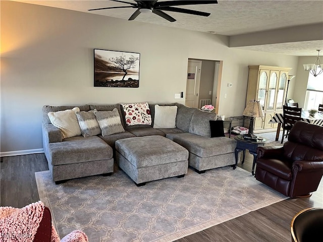 living room featuring baseboards, a textured ceiling, wood finished floors, and ceiling fan with notable chandelier