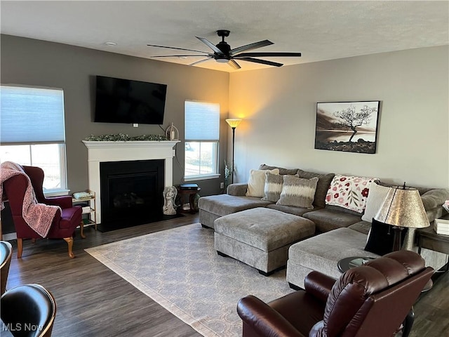 living area with a ceiling fan, a fireplace with flush hearth, and wood finished floors