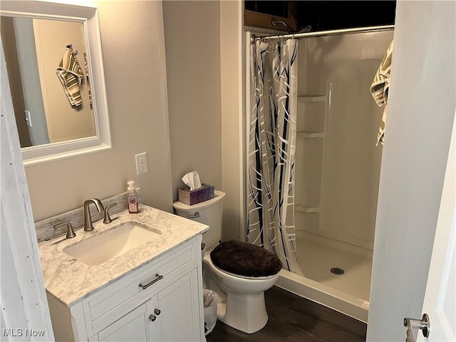 bathroom featuring a shower stall, vanity, toilet, and wood finished floors