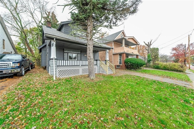 view of front facade with covered porch, a chimney, and a front yard