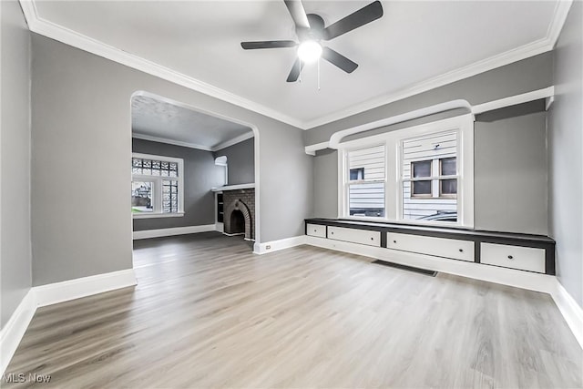 unfurnished living room featuring visible vents, a brick fireplace, crown molding, baseboards, and wood finished floors